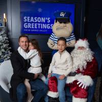 Parents with three kids smile with Santa and Louie
